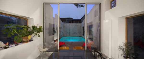 Dans le prolongement du séjour, le patio et sa piscine se dessinent derrière une baie en double-hauteur. / Edouard Decam